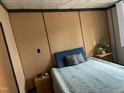 Comfortable bedroom featuring paneled walls, a bed with blue headboard, and simple decor for a cozy retreat at 117 Lone Star Dr, Louisburg, NC 27549