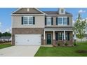Two-story home featuring brick and siding, a two-car garage, and a charming covered front porch at 168 Paper Birch Way, Fuquay Varina, NC 27526