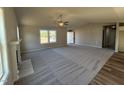 Spacious living room with a fireplace, ceiling fan, plush gray carpet, and large windows offering ample natural light at 175 Magnolia Run Way, Benson, NC 27504