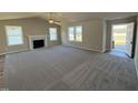 Spacious living room with a fireplace, ceiling fan, plush gray carpet, and large windows offering ample natural light at 175 Magnolia Run Way, Benson, NC 27504