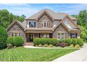 Stately stone-and-siding home featuring lush landscaping, a manicured lawn, and a covered porch at 2933 Elmfield St, Raleigh, NC 27614