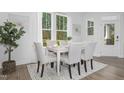 Bright dining room featuring a white table, six upholstered chairs, light wood floors, and a large window with natural light at 312 Church St # 36, Wendell, NC 27591