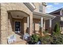 Inviting front porch with brick columns and a cozy seating area and decorative plants at 330 Macallan Dr, Burlington, NC 27215