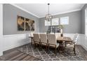 Elegant dining room featuring a large wooden table, modern chandelier, wainscoting, and patterned rug at 132 Mystic Pine Pl, Apex, NC 27539