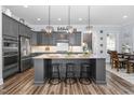 Modern kitchen with gray cabinets, granite countertops, an island with seating, and stainless steel appliances at 132 Mystic Pine Pl, Apex, NC 27539