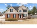 Charming two-story home featuring tan siding, red brick accents, and black shuttered windows at 18 Orangewood Court Ct, Lillington, NC 27546