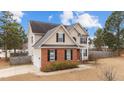 Charming two-story home featuring tan siding, red brick accents, and black shuttered windows at 18 Orangewood Court Ct, Lillington, NC 27546