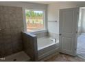 Bright bathroom featuring a soaking tub with tiled surround and window view at 249 Tidal Pool Way, Cary, NC 27519