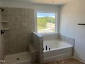 Bathroom featuring a soaking tub, a tiled shower with a window, and modern fixtures at 253 Tidal Pool Way, Cary, NC 27519