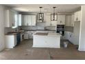 Bright kitchen with white cabinets, large island, stainless appliances, and designer light fixtures at 253 Tidal Pool Way, Cary, NC 27519