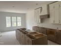 Bright kitchen area with white cabinets, a gray island, and large windows at 395 Meadow Walk Dr, Fuquay Varina, NC 27526