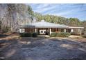 A sprawling ranch house with a metal roof and lush green bushes at 4100 Durham Rd, Raleigh, NC 27614