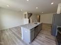 Open concept kitchen with granite countertops, gray cabinetry, stainless steel appliances, and wood-look flooring at 6132 Arsenal Ave, Raleigh, NC 27610