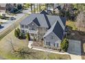 Aerial view of a two-story home with a driveway, basketball hoop and mature trees at 1013 Timber Mist Ct, Cary, NC 27519