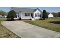 View of the home showing a long concrete driveway, well-manicured lawn and mature landscaping at 104 Eddy Ct, Benson, NC 27504