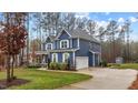 Blue home with white trim, a two-car garage, well manicured lawn and mature landscaping at 130 Willow Bend Dr, Youngsville, NC 27596