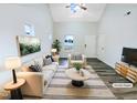 Bright, staged living room with modern furnishings, hardwood floor, and a vaulted ceiling at 1628 Beacon Village Dr, Raleigh, NC 27604
