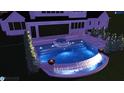 Night view of a stunning pool featuring a unique water feature, integrated spa, and elegant lounging area in backyard setting at 6500 Century Oak Ct, Raleigh, NC 27613