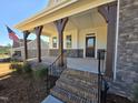 Inviting front porch with brick steps, stone pillars, and black railings at 1021 Prominence Dr., Homesite 20, Durham, NC 27712