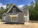 Side view of gray house featuring a garage and stone detailing, set against a backdrop of lush trees at 1224 Red Cedar Ct # 33, Youngsville, NC 27596