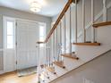 Inviting foyer featuring hardwood floors, staircase with white spindles and wood rail, and bright, natural lighting at 304 Northbrook Dr, Raleigh, NC 27609