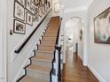 Elegant staircase with carpet runner, dark wood banister, and gallery wall of art and photos at 3343 Ridgecrest Ct, Raleigh, NC 27607