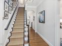 Elegant staircase with carpet runner, dark wood banister, and gallery wall of art and photos at 3343 Ridgecrest Ct, Raleigh, NC 27607