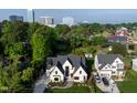 Aerial view of a modern home with well-manicured lawn, mature trees, and a cityscape backdrop at 4329 Lambeth Dr, Raleigh, NC 27609