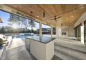 Covered outdoor living area featuring an outdoor kitchen, fireplace, ceiling fans, and views of the pool at 4329 Lambeth Dr, Raleigh, NC 27609