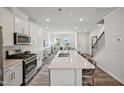 Spacious kitchen flows into the living area, featuring a large island with seating and stainless steel appliances at 683 Mirkwood, Apex, NC 27523