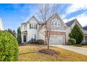 Two story home with stone facade, two car garage, manicured lawn and a lovely tree at 1005 Forest Willow Ln, Morrisville, NC 27560