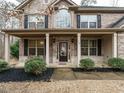 Inviting front porch featuring a seating area, black mulch beds, and a glass-paneled front door at 104 Black Swan, Youngsville, NC 27596