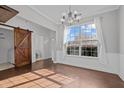 Dining area featuring hardwood floors, a large window, chandelier and a barn door at 1217 Maroon Dr, Durham, NC 27713