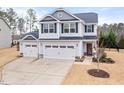 Charming two-story home with a wide driveway and three-car garage surrounded by lush trees at 176 E Ravano Dr, Clayton, NC 27527