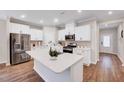 Modern kitchen boasts white cabinets, stainless steel appliances, a large island, and stylish backsplash, providing a perfect cooking space at 186 Madden Rose Loop, Garner, NC 27529