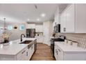 Bright kitchen featuring stainless steel appliances, white cabinets, a farmhouse sink and patterned backsplash, creating an inviting space at 186 Madden Rose Loop, Garner, NC 27529