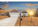 Inviting single-Gathering home with an attached garage, a paved driveway, and a manicured lawn at sunset at 229 S Prince Henry Way Way, Cameron, NC 28326