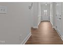 Hallway featuring wood-look flooring, fresh neutral paint, and views of the home's front entrance at 229 S Prince Henry Way Way, Cameron, NC 28326