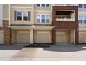 Condo exterior featuring tan siding, brick accents, and attached garages; a comfortable and convenient place to call home at 2810 Bedford Green Dr # 300, Raleigh, NC 27604