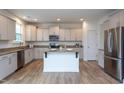 Bright kitchen with stainless appliances, island, granite counters, and wood-look flooring at 3429 Ferdilah Ln, Raleigh, NC 27610