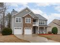 Traditional home featuring stone accents, gray siding, a two-car garage, and a front porch at 509 Arbor Crest Rd, Holly Springs, NC 27540