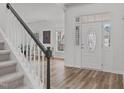 Bright foyer showcasing hardwood floors, a decorative door, and staircase with white spindles at 509 Arbor Crest Rd, Holly Springs, NC 27540