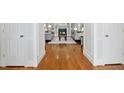 Hallway view shows hardwood floors leading to living room with fireplace and grey sofas at 5204 Winter Holly Ct, Raleigh, NC 27606