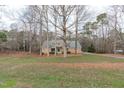 View of a brick home nestled among mature trees and a sprawling front lawn, creating a serene setting at 5512 Spring Bluffs Ln, Raleigh, NC 27606