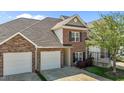 Charming two-story brick townhouse featuring a two-car garage, black shutters, and landscaped yard at 638 Village Lake Dr, Mebane, NC 27302