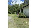 Shows the side exterior with a small covered porch, green bushes, and a gravel driveway at 652 Old Sanford Rd, Moncure, NC 27559