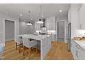Bright kitchen boasts a waterfall island, pendant lighting, stainless steel appliances, and sleek white cabinets at 809 Tower St, Raleigh, NC 27607