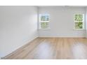 Bright bedroom with two windows and light wood flooring, creating a clean and airy atmosphere at 101 Hiddenite Pl, Holly Springs, NC 27540