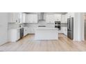 Modern kitchen featuring white cabinets, stainless steel appliances, and a large center island with seating at 101 Hiddenite Pl, Holly Springs, NC 27540