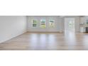Spacious living room featuring light wood flooring and three large windows overlooking the backyard at 101 Hiddenite Pl, Holly Springs, NC 27540